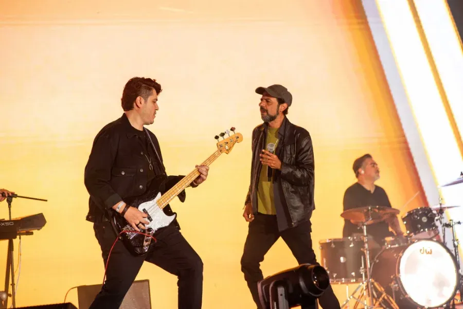 Bohemia Suburbana en el escenario: el bajista y el vocalista frente a una pantalla iluminada, con la batería al fondo.