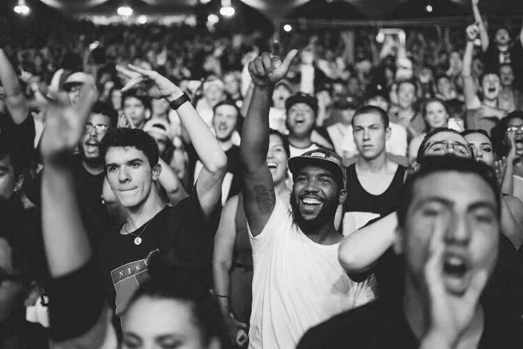 Público celebrando en un concierto, en blanco y negro.