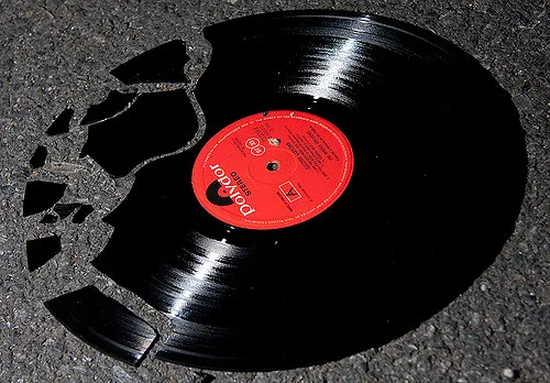 Disco de vinilo roto sobre el asfalto.