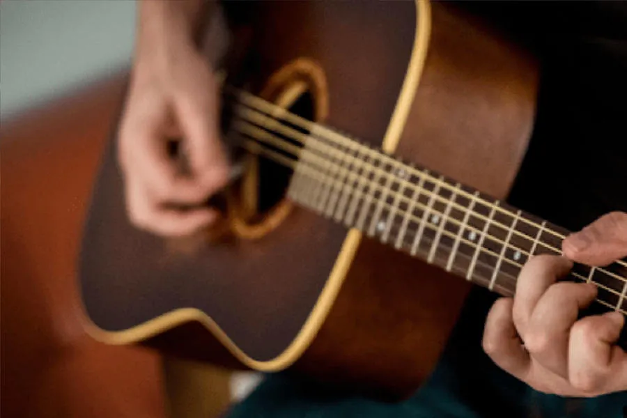 Manos tocando una guitarra acústica.